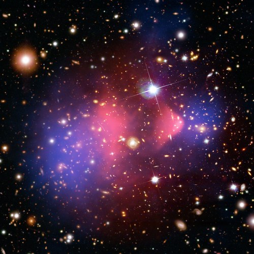 A composite image of the Bullet Cluster, where two blue clumps of dark matter flank the pink X-ray gas left behind after two galaxy clusters collided.