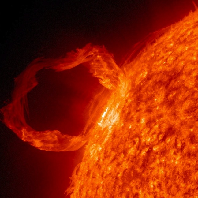 A picture of a solar flare erupting from the surface of the Sun in the shape of a loop.